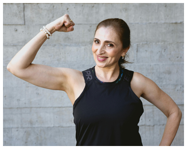 A smiling woman flexing her arm.