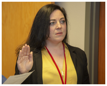 A woman with a raised right hand, taking an oath.
