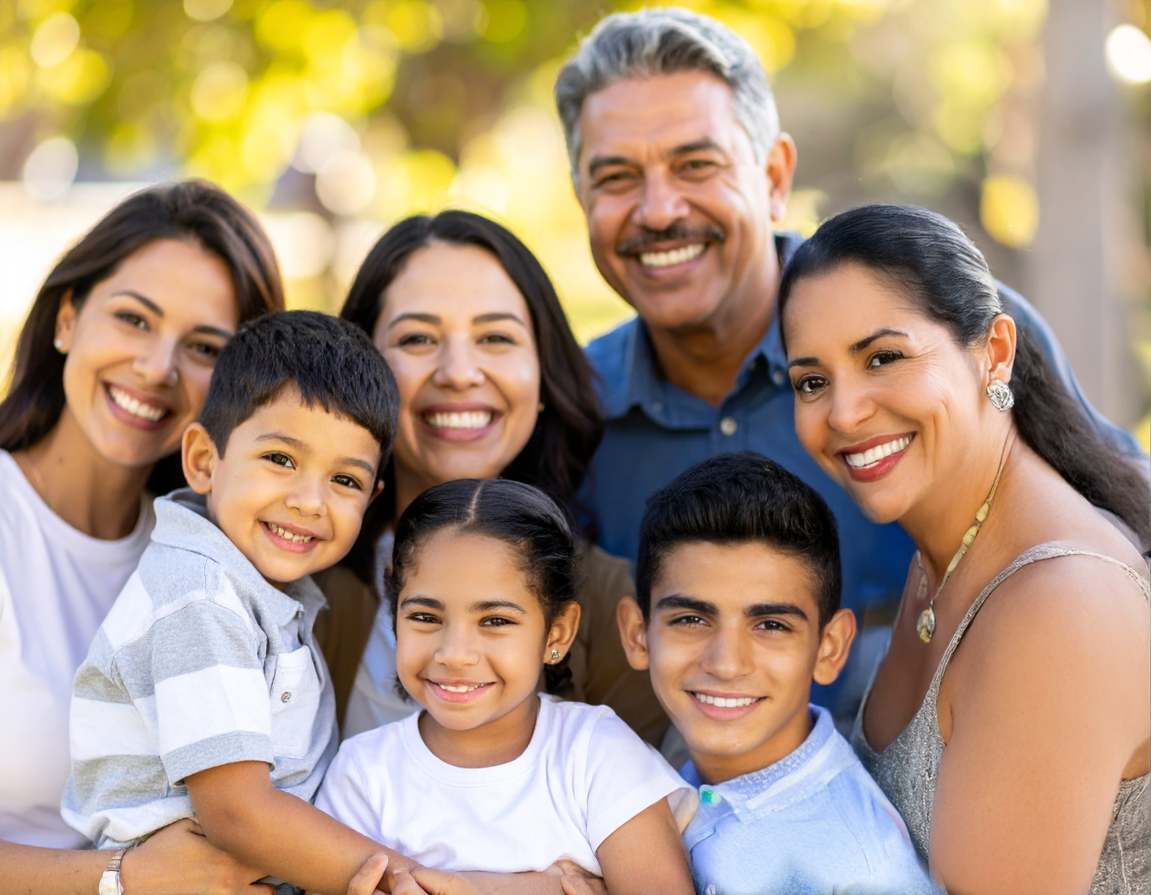 Family portrait of a Hispanic family with twin older sisters, a father, mother, teenage boy, nine-year-old sister, and three-year-old brother.