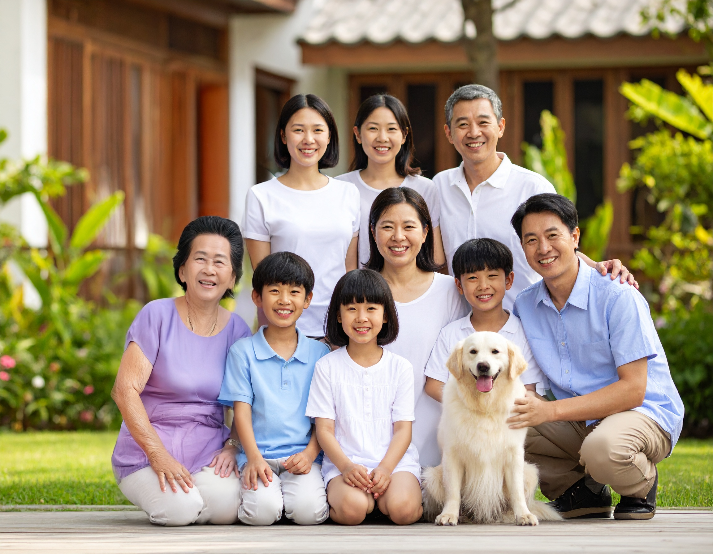 Family portrait of a Vietnamese family, showing two older daughters, a grandfather, two parents, two young sons, a young daughter, a dog, and a grandmother.