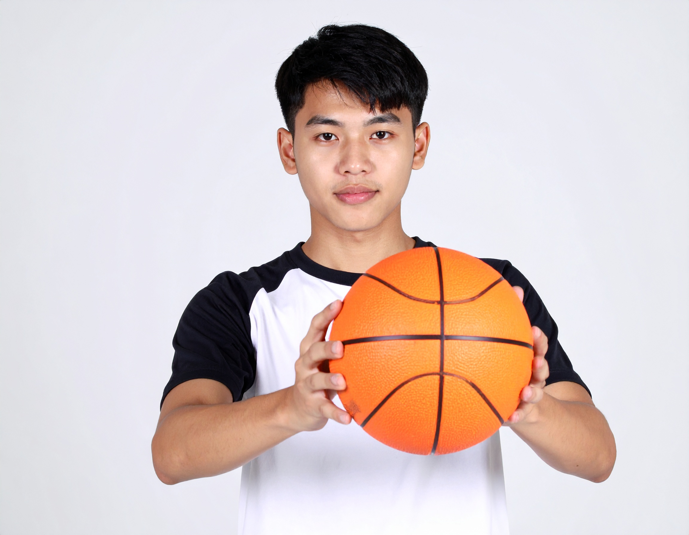 A young Chinese teenager holding a basketball.