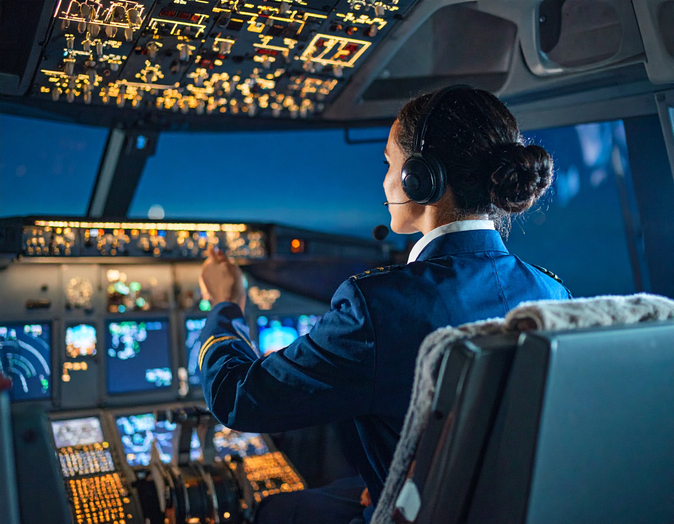A female pilot in the cockpit of a plane at night.