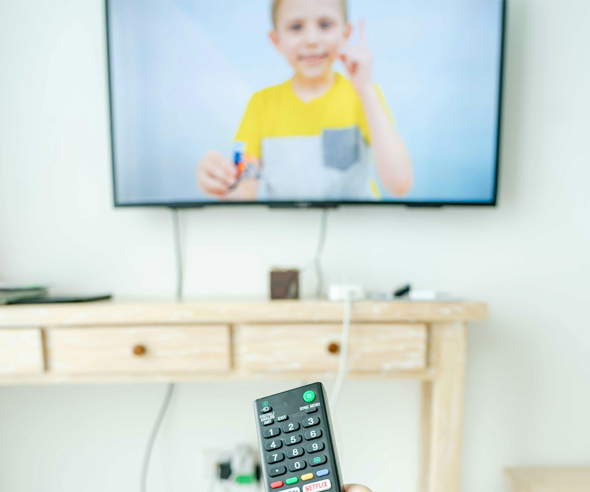 A person holding a remote in front of a TV.