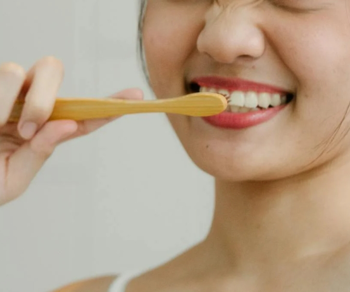 A woman brushing her teeth with a toothbrush.
