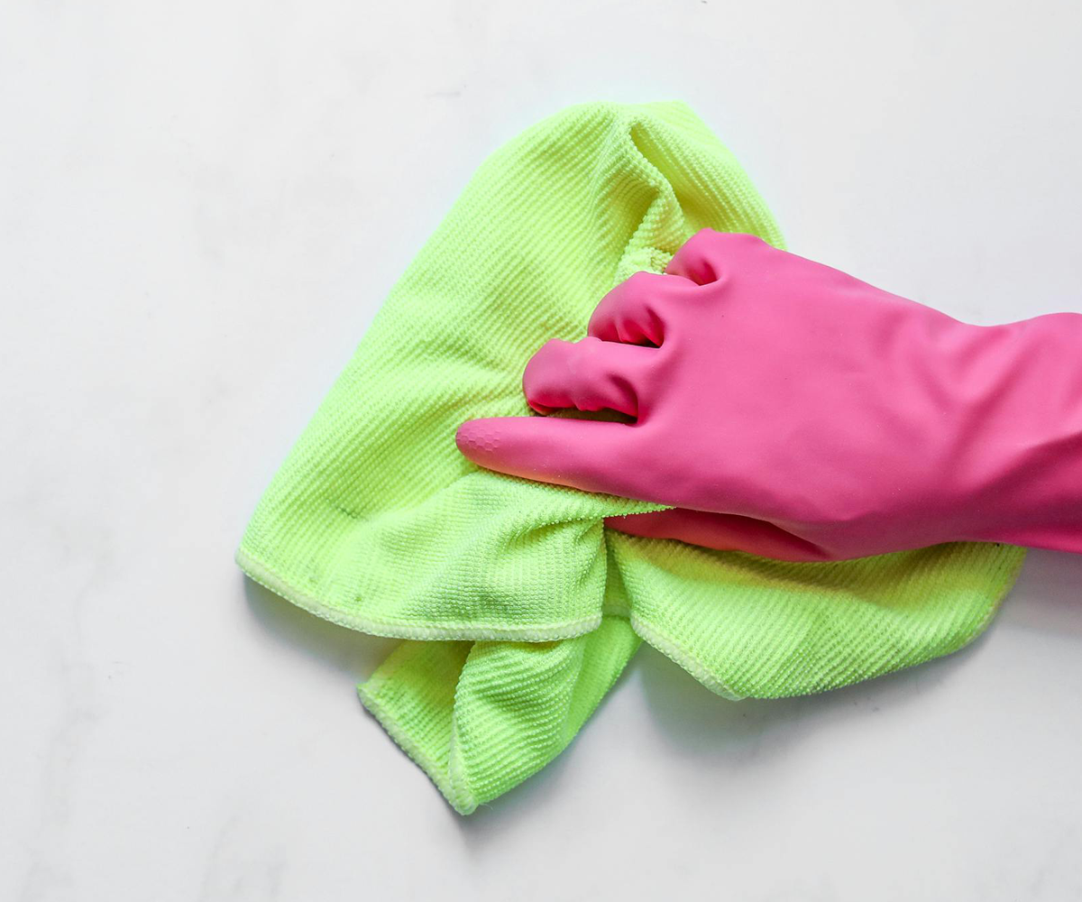 A gloved hand wiping a surface with a cloth.