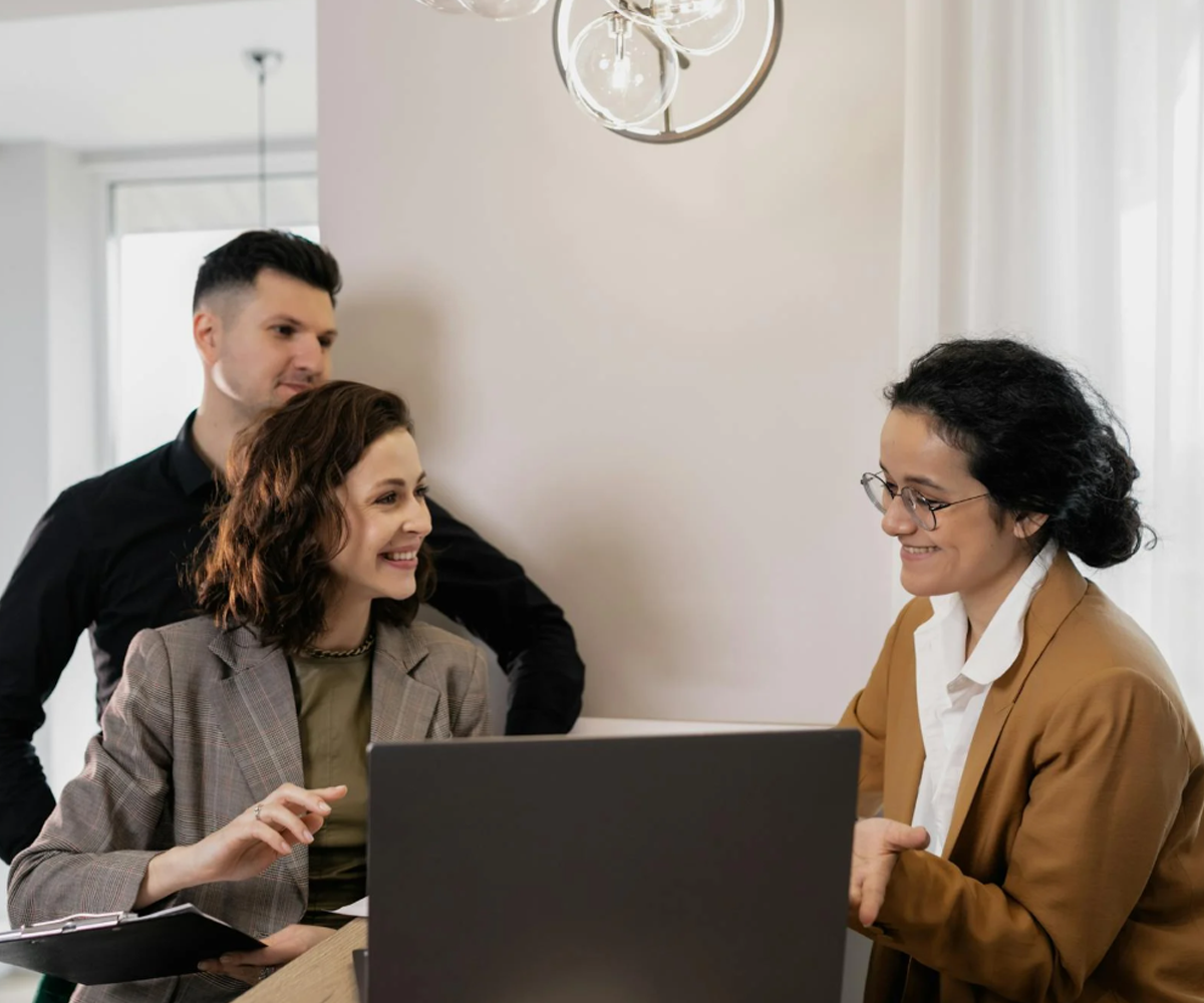 A professional woman sitting at a table with two clients.