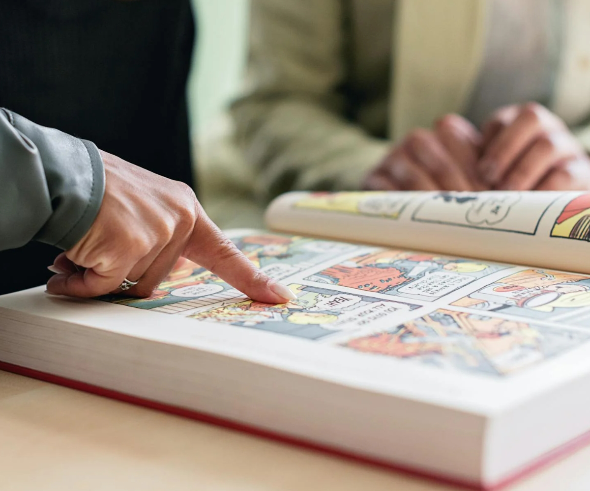 A person pointing to a page in a comic book.