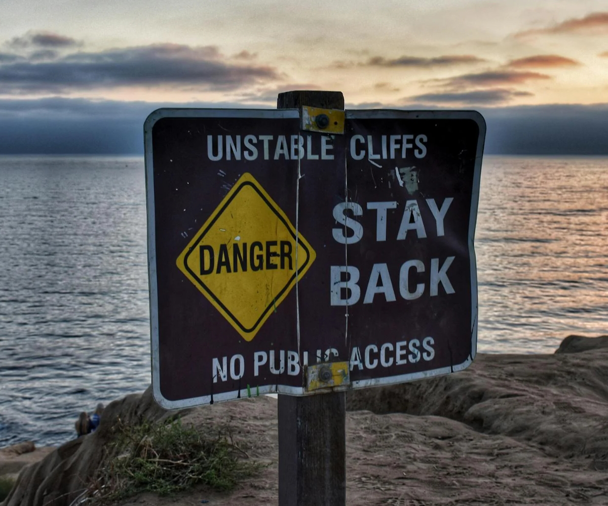 A sign that reads 'unstable cliffs, danger, stay back, no public access.'