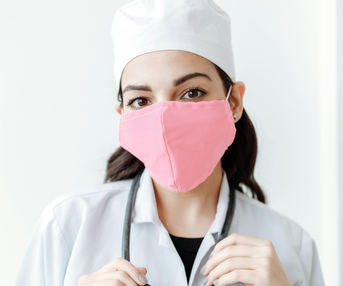 A female doctor wearing a medical mask, stethoscope, and white lab coat.
