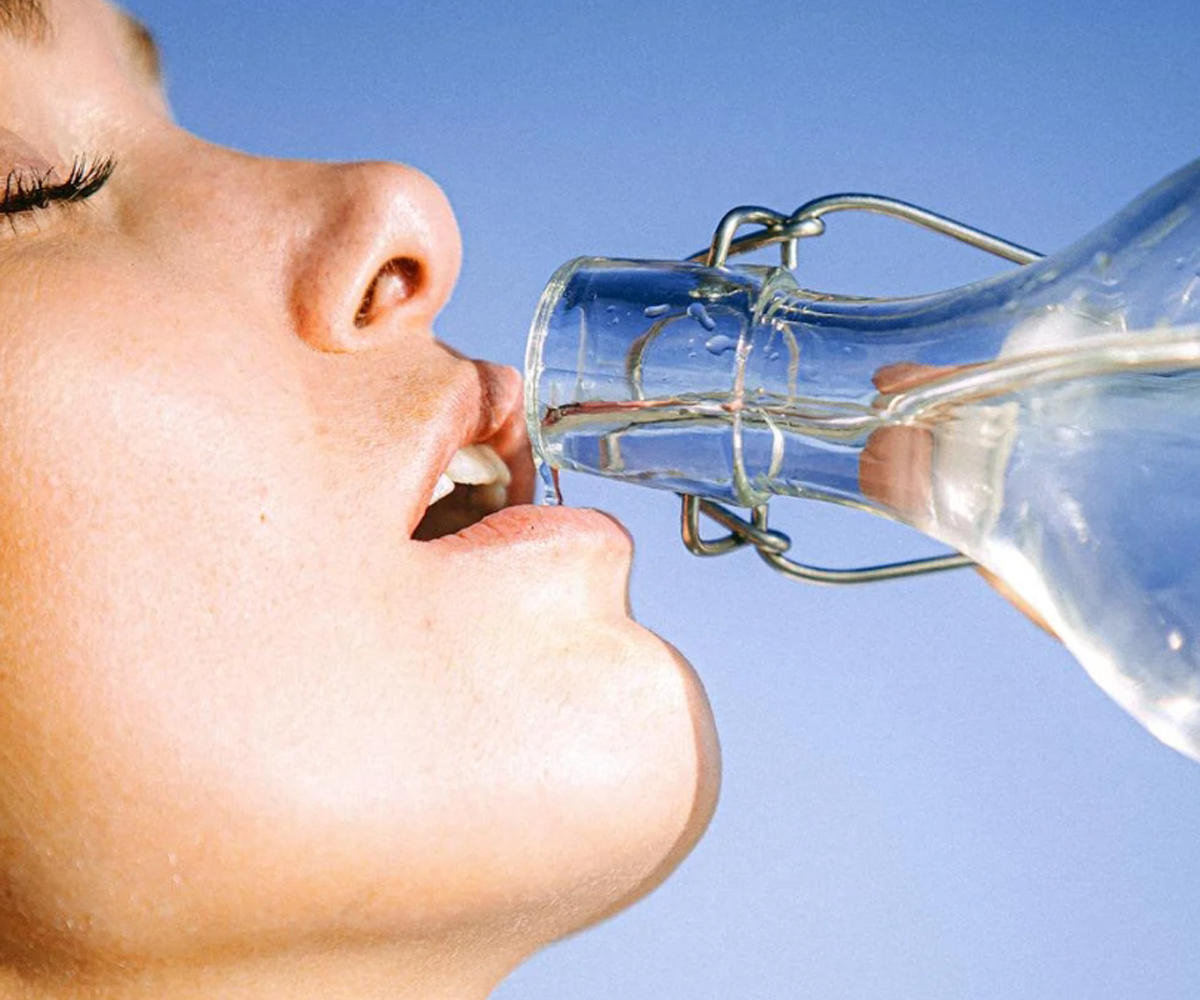A woman drinking from a bottle of water.