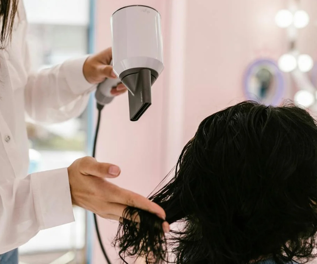 A person blow drying a woman's hair.