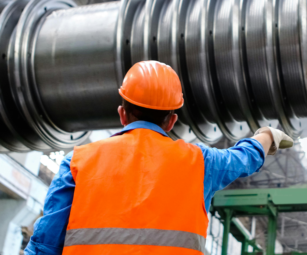 An engineer wearing a hard hat, examining machinery.