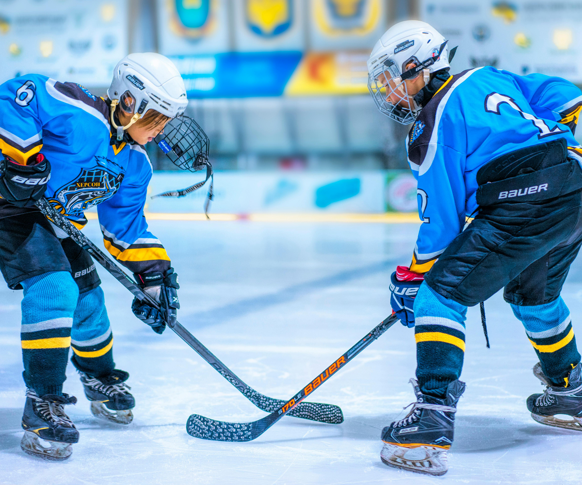 Two people playing hockey on an ice rink.