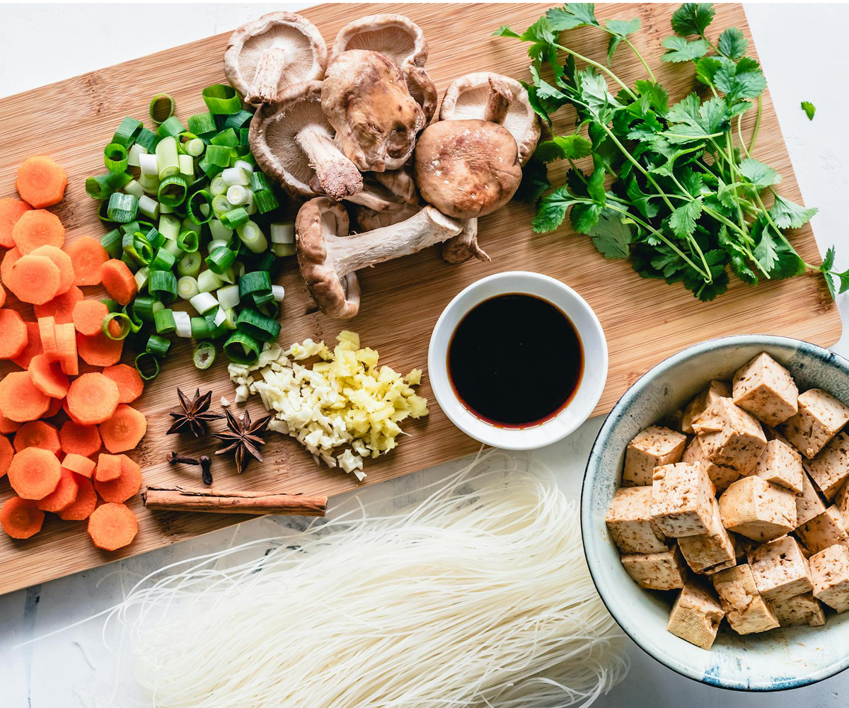 A kitchen counter with an assortment of vegetables and ingredients.