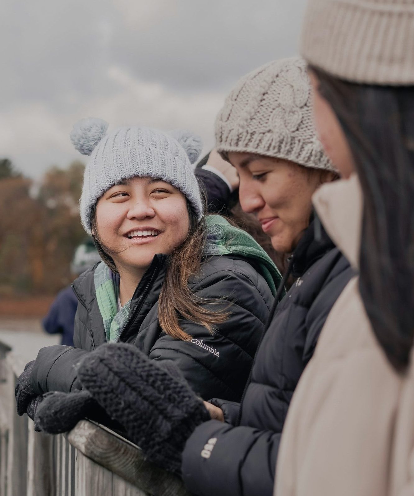 A group of friends wearing winter hats, winter coats, and mittens.