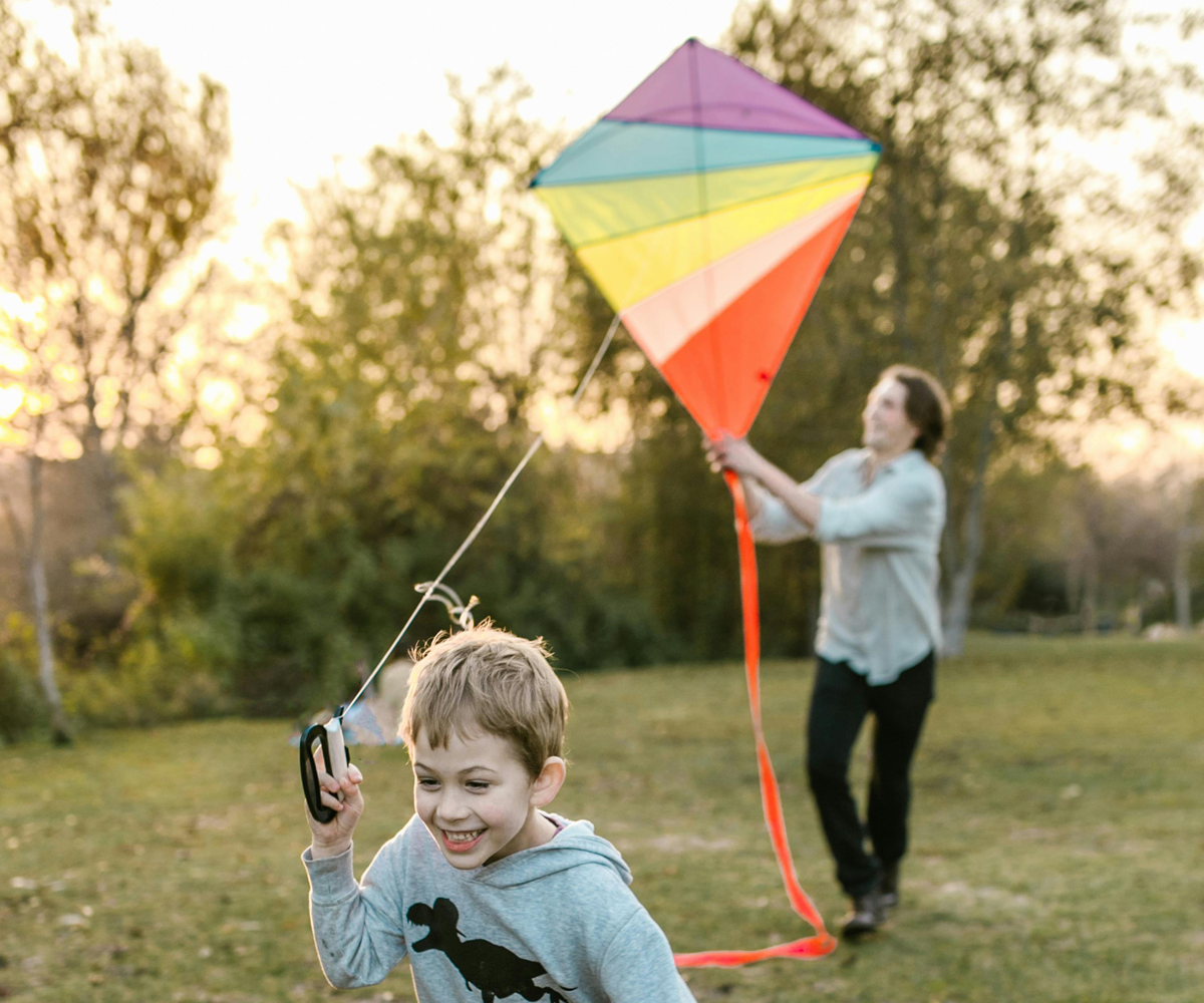 A child and a man flying a kit outside.