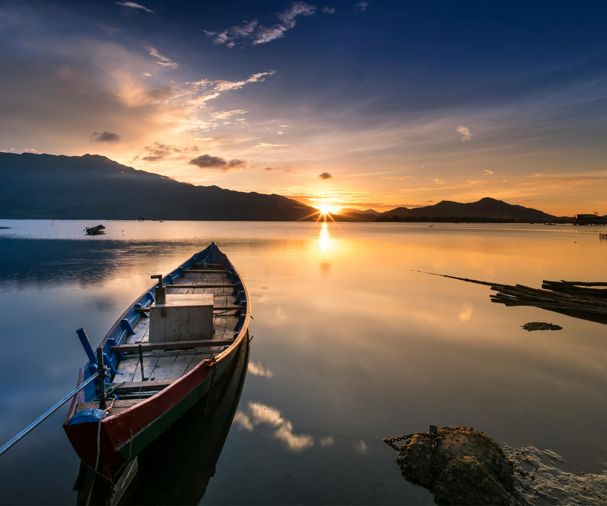 A canoe on a lake in front of a sunset.