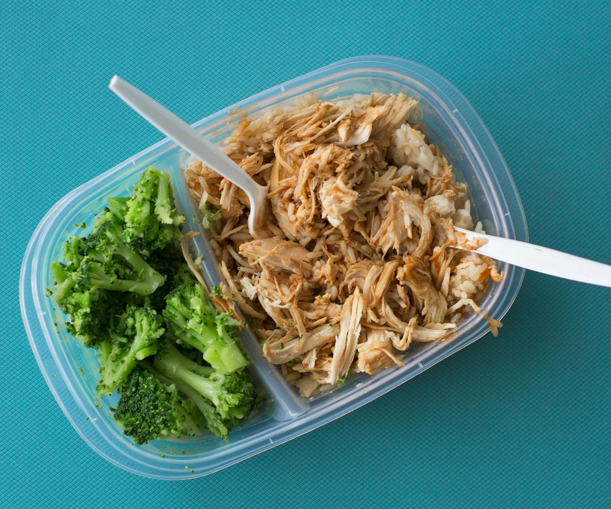 A plastic container of tuna and broccoli.