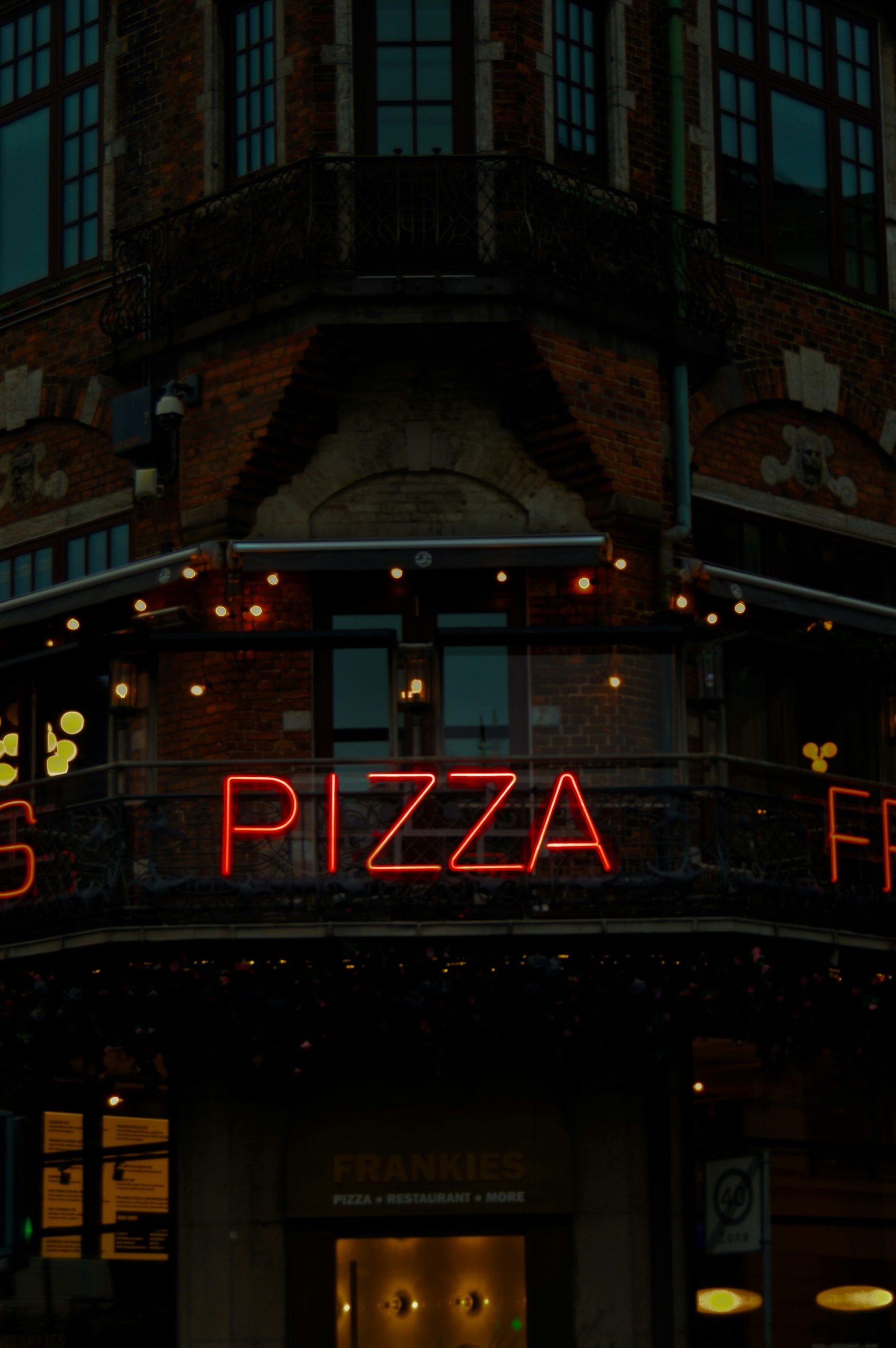 A neon sign for a pizza shop at night.