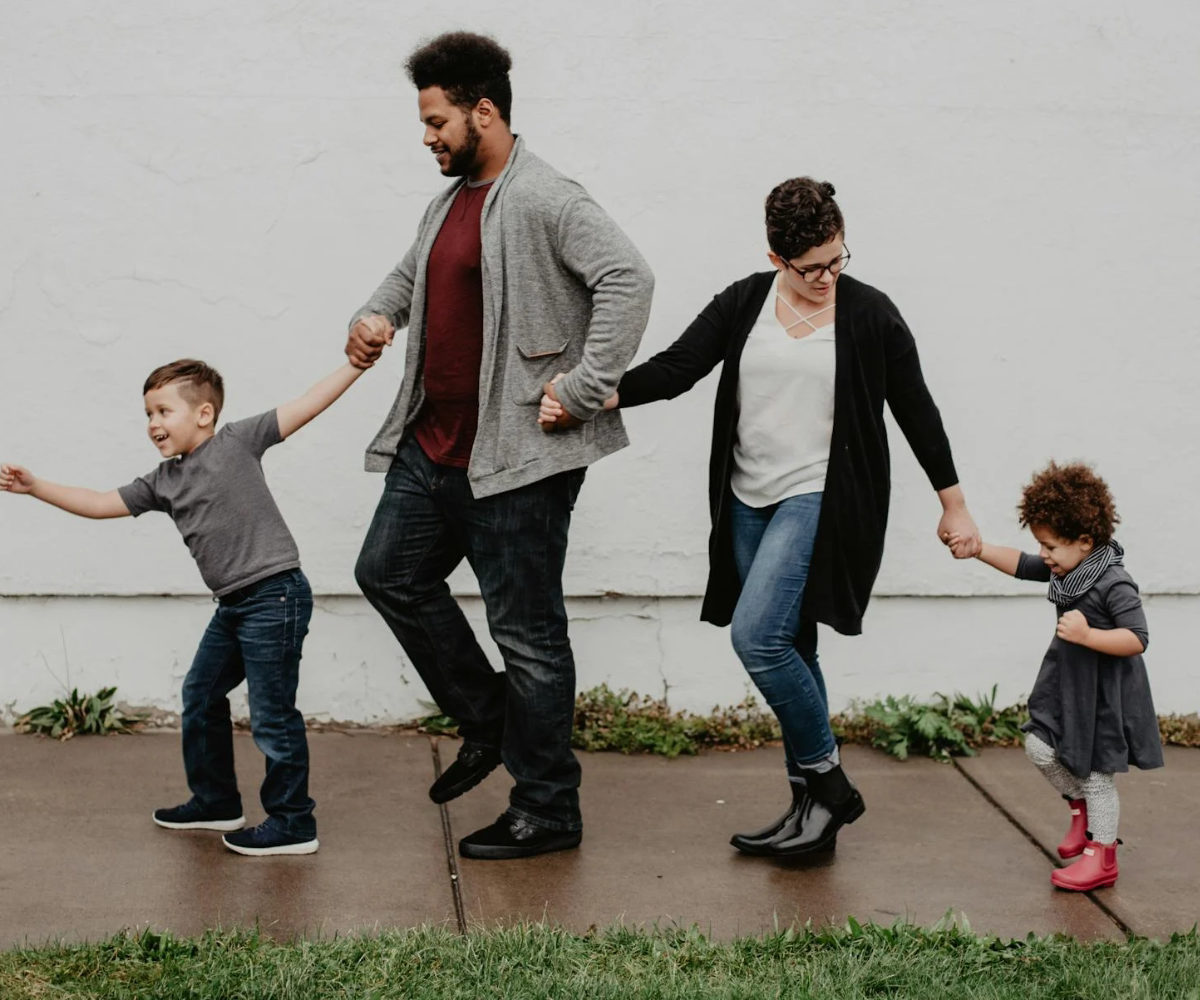 Two parents leading two small children.