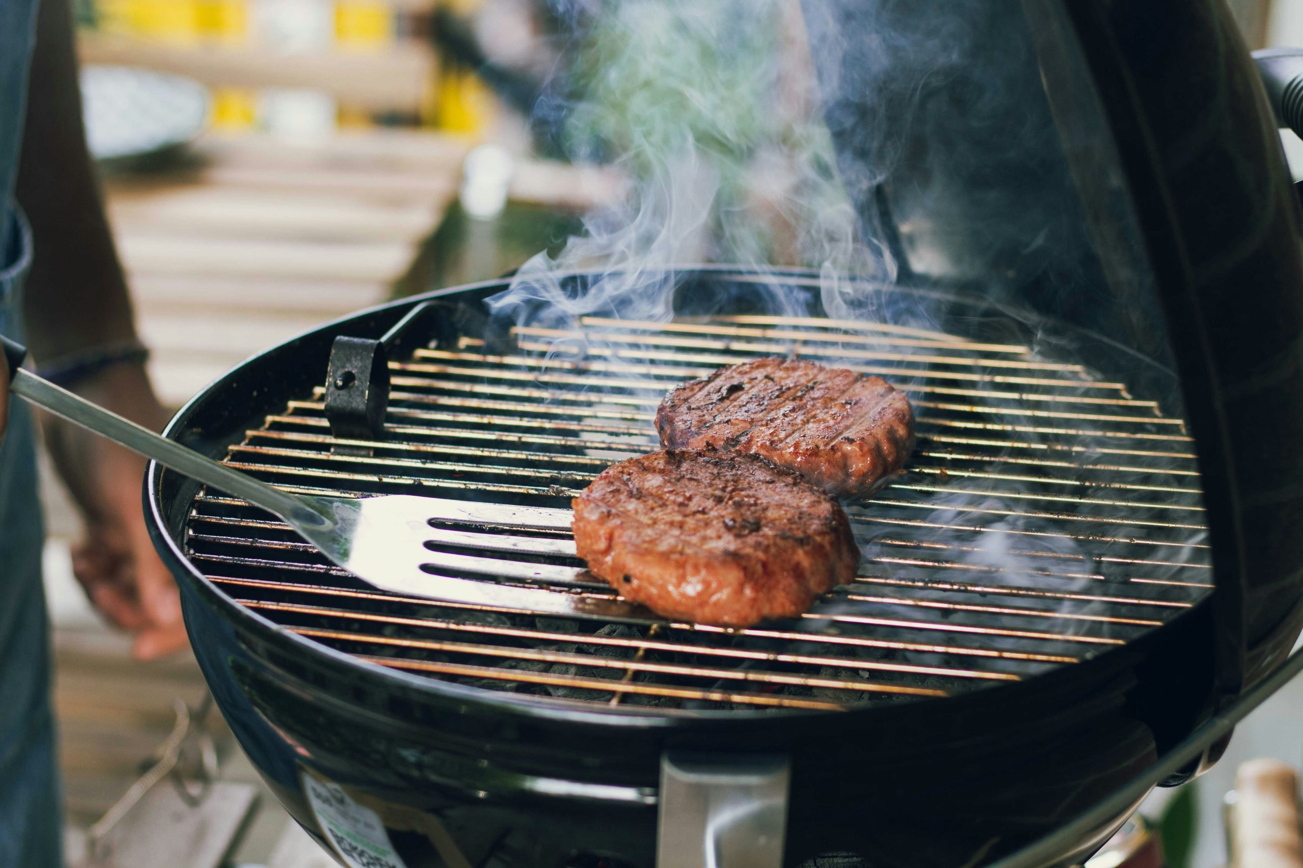 Two hamburger patties cooking on an outdoor grill.