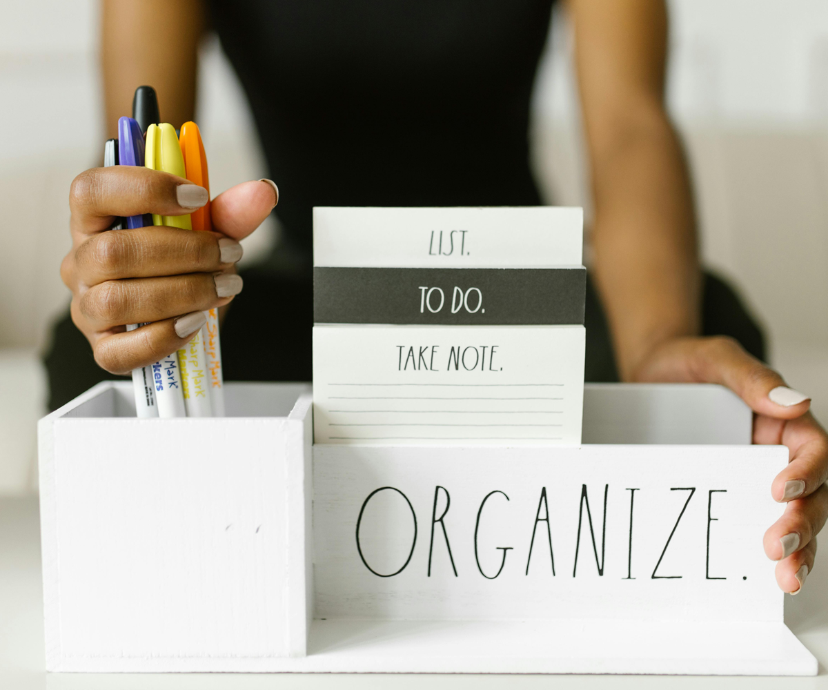 A woman organizing pens into a desktop organizer that reads 'organize.'