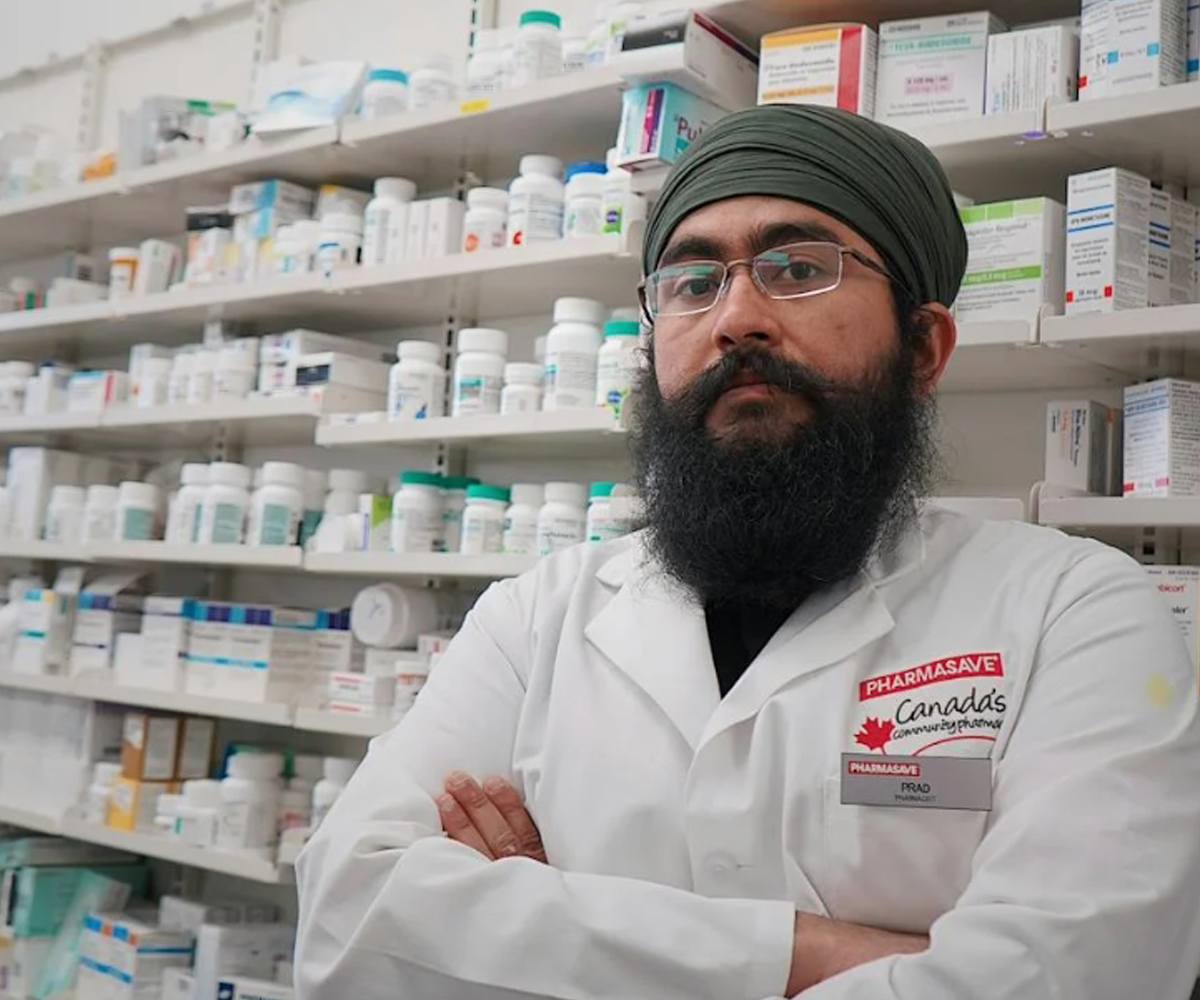 A pharmacist standing in front of shelves of medicine.