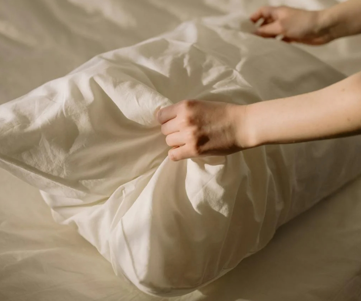 A person smoothing a white pillowcase.