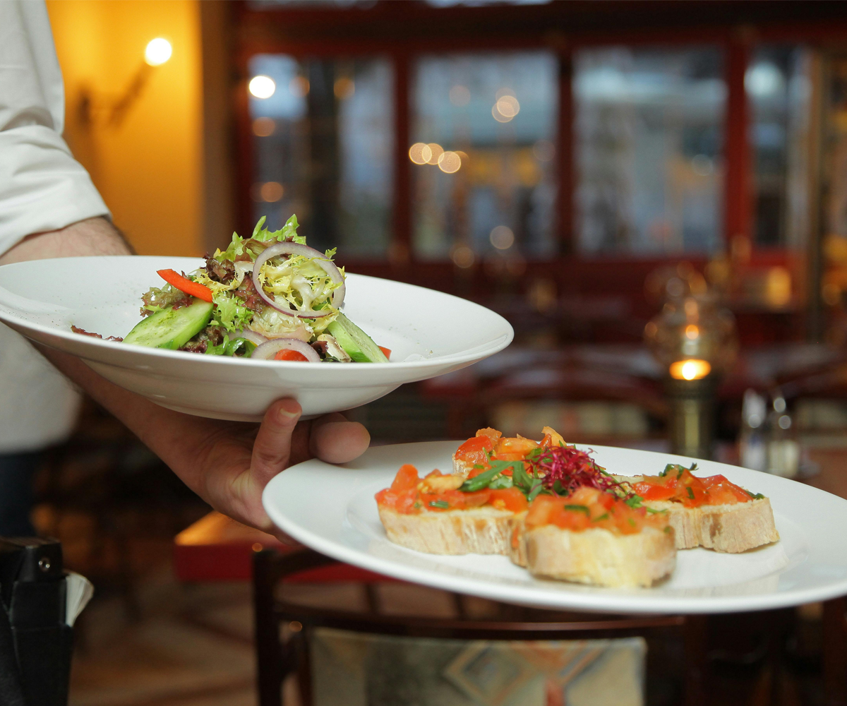 A server bringing plates at a restaurant.
