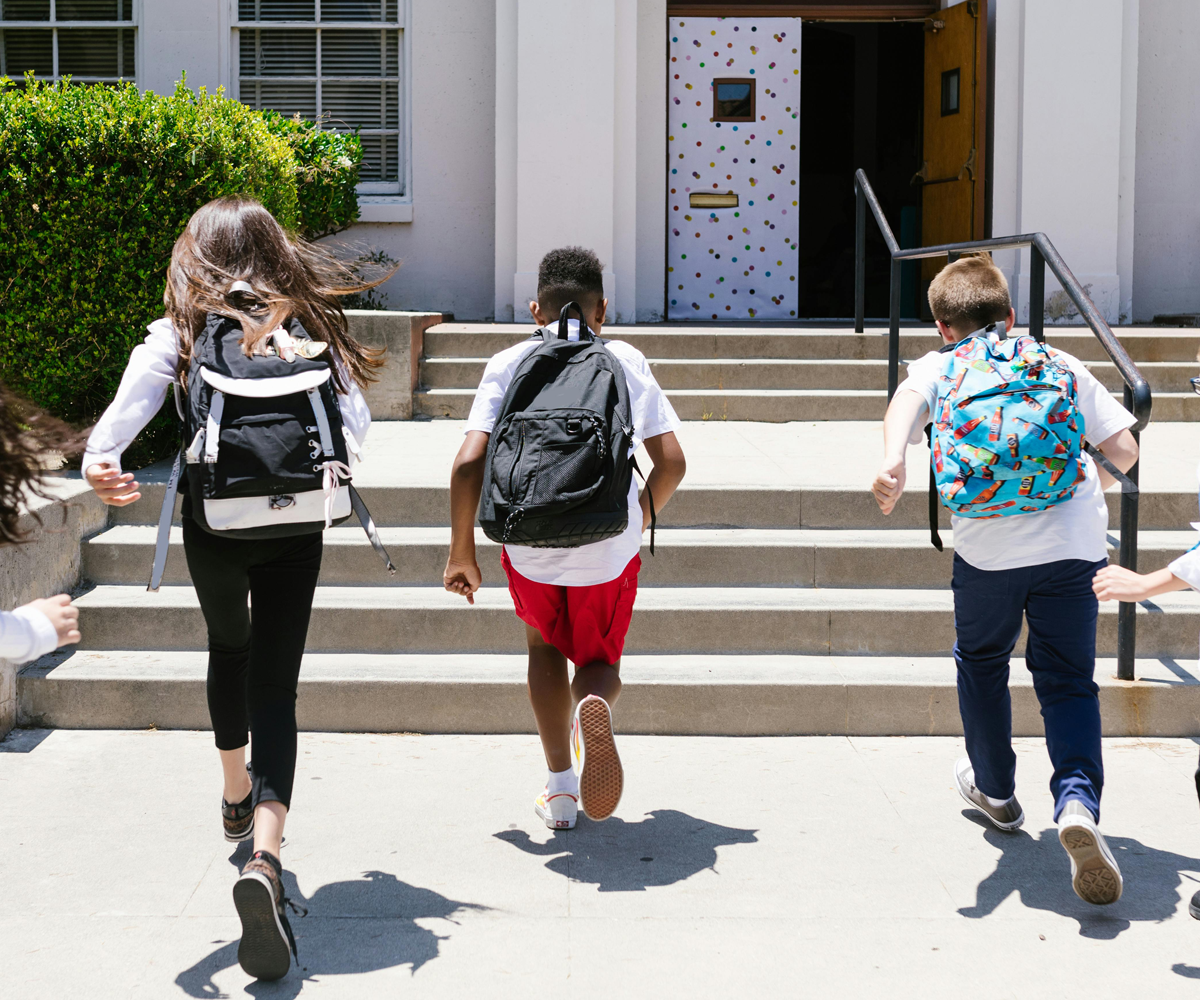 A group of schoolchildren running into a school entrance.