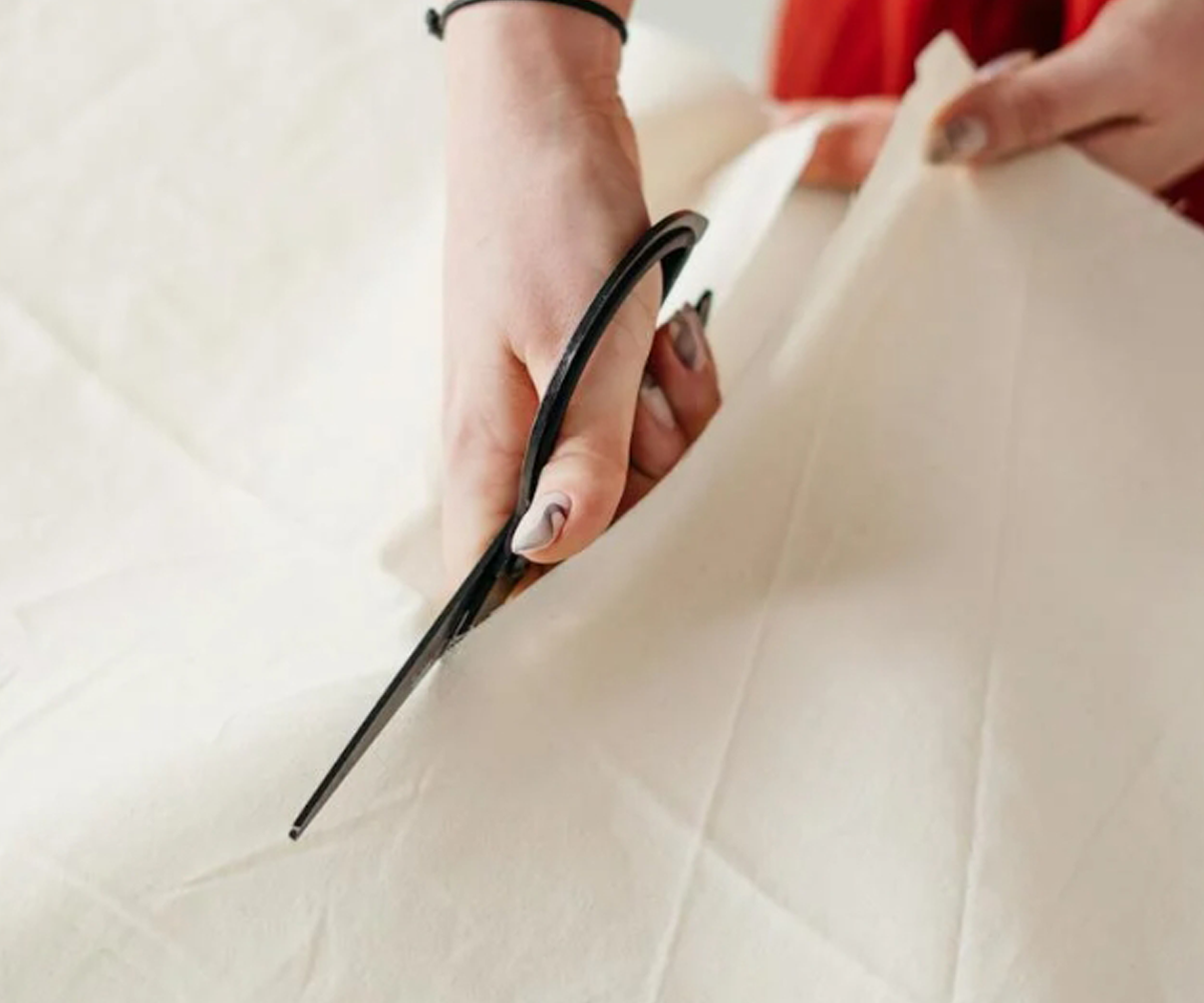 A person cutting fabric with scissors.