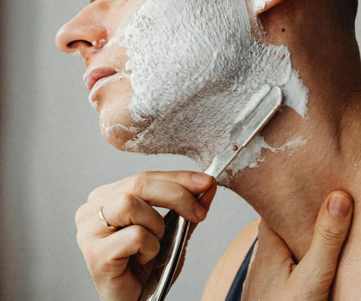 A man shaving his face with a razor blade.