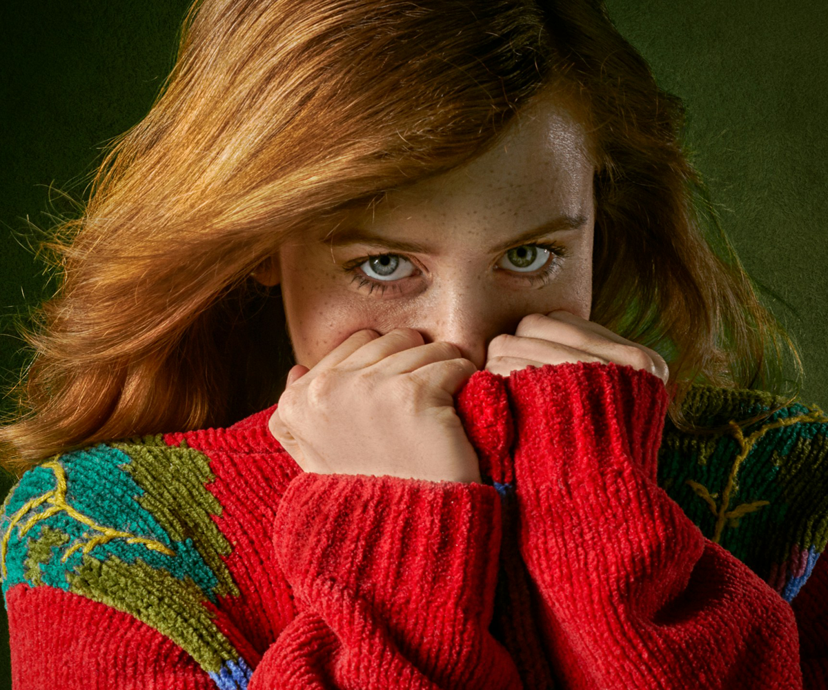 A shy woman covering her face with her hands.