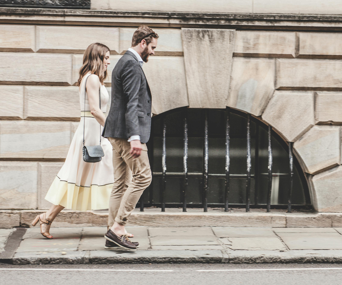Two people walking on a sidewalk.