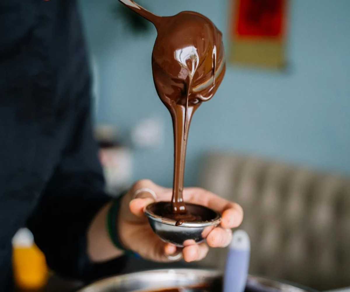 A person dripping chocolate sauce with a spoon.