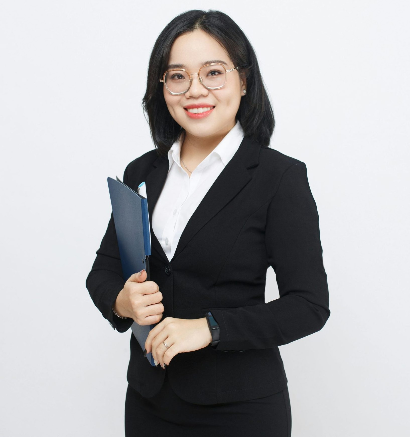 A young woman wearing glasses and a business suit, holding a folder.