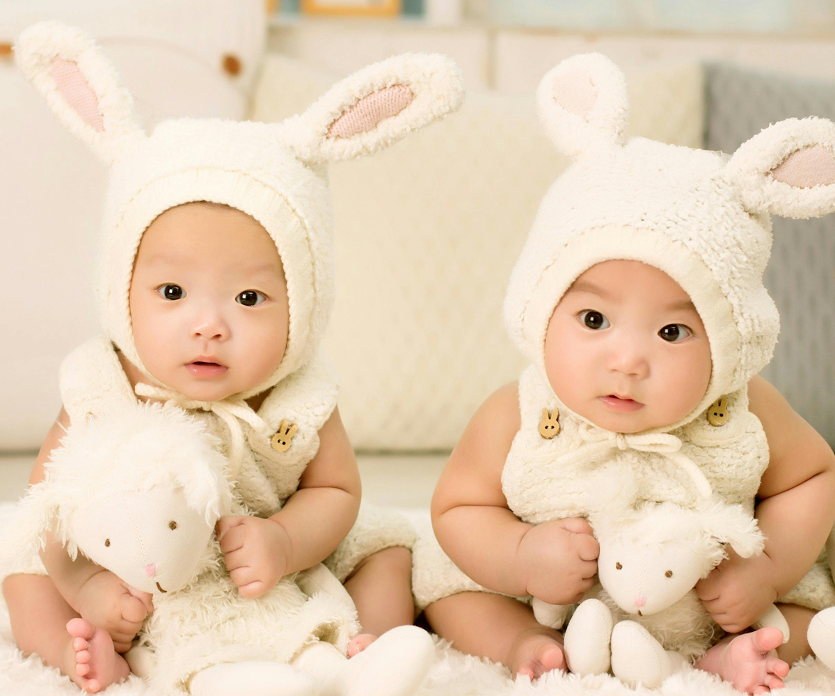 Two twin babies sitting next to each other.