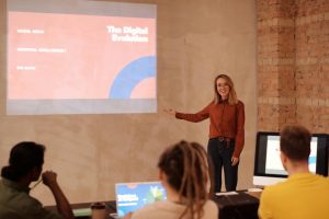 A woman presenting to a group in front of a screen.