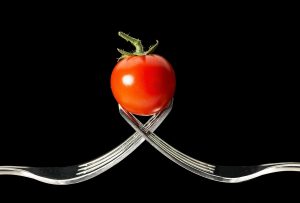image of a small tomato held up by two forks