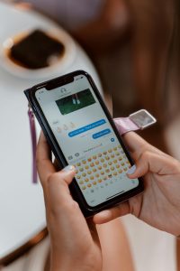 A person holding cellphone displaying the list of emoji options when sending a text.