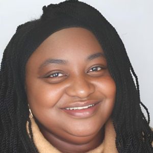 Portrait of a black-haired woman with a dark skin tone, wearing yellow clothes.