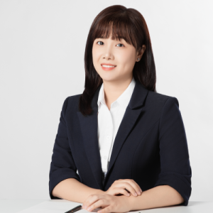An East Asian woman with black hair and a light skin tone, wearing a black suit.