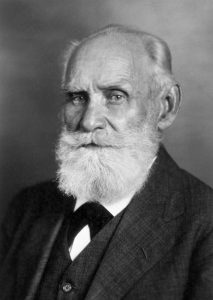 Ivan Pavlov, an older man appears in black and white, wearing a three-piece suit and a thick white beard.