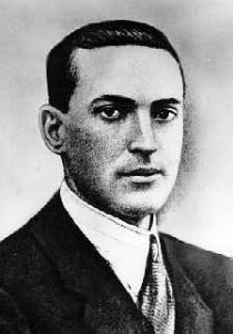 A black and white photo of a young Lev Vygotsky looking at the camera wearing clean-cut hair and suit and tie.