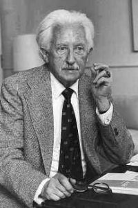 Erik Erikson, an older white man pictured here in a suit and tie, leaning against his desk