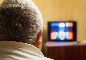 Man with gray hair watching a TV