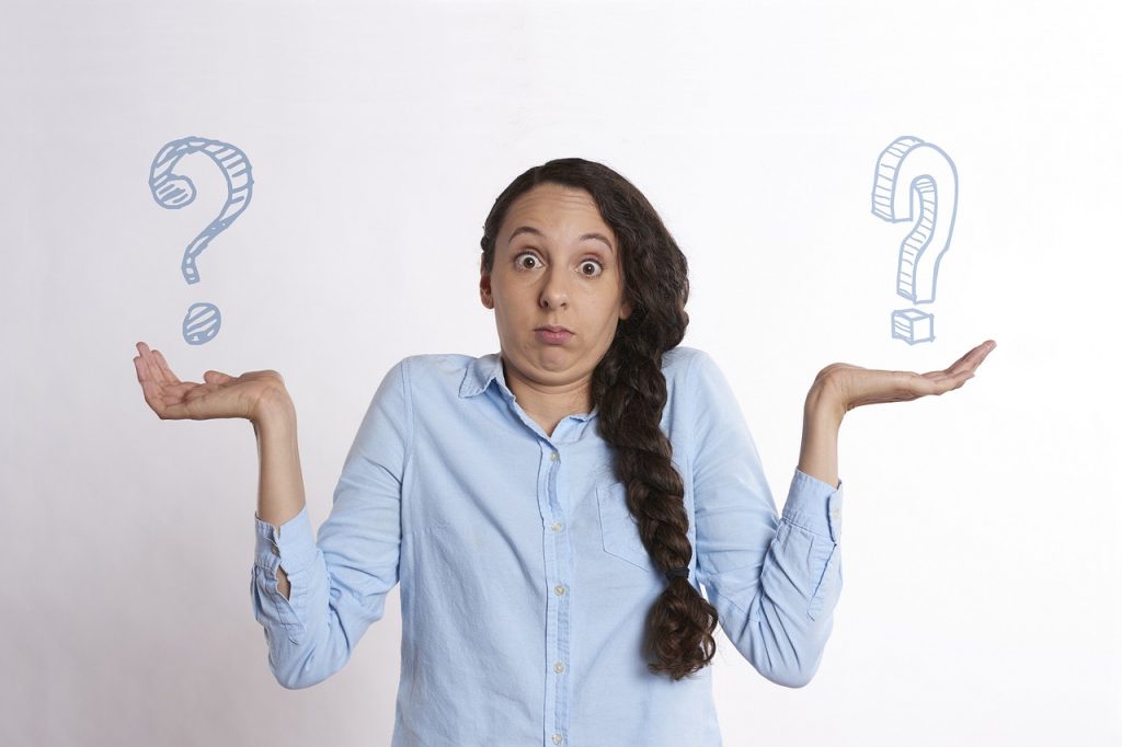 Women with hands out at sides holding question marks in each hand