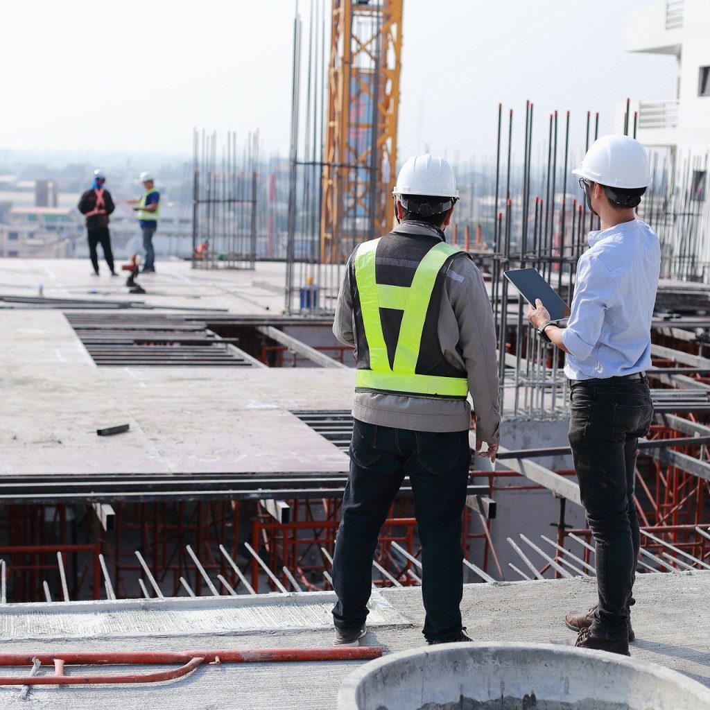 Two construction workers standing on top of a half built skyscraper