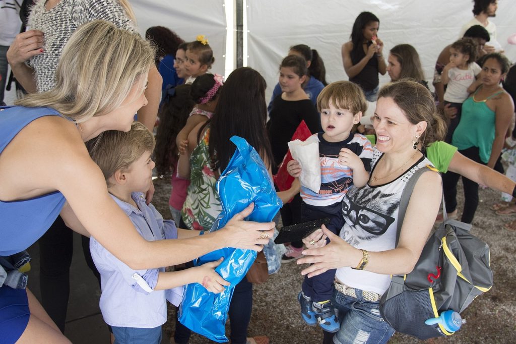 Woman handing out gift packages to parents and children