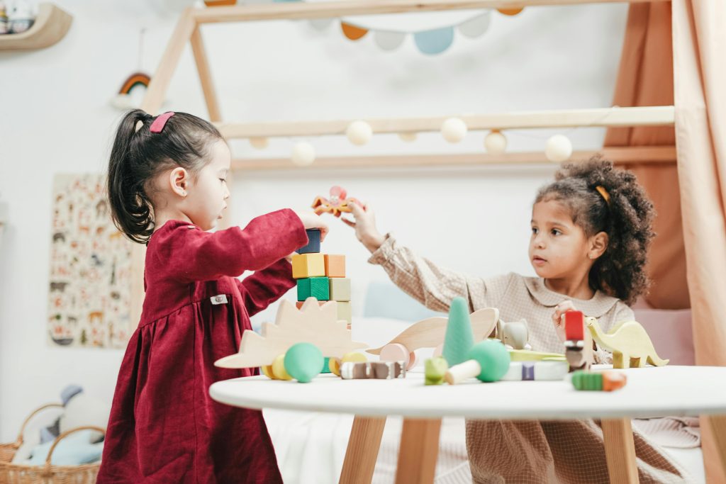 Two children playing, sitting at a table with toys